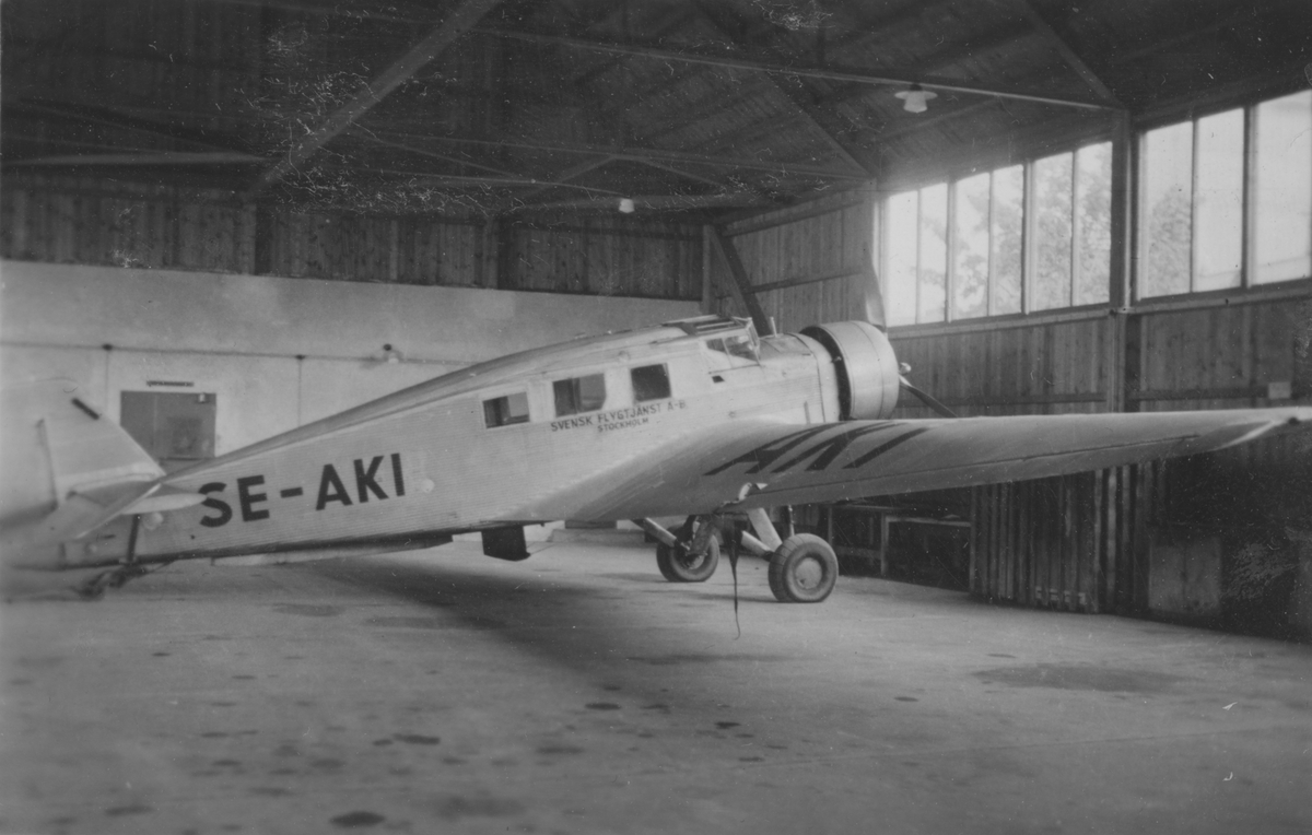 Civilt flygplan Junkers W 34ho märkt SE-AKI tillhörande Svensk flygtjänst står i en hangar.