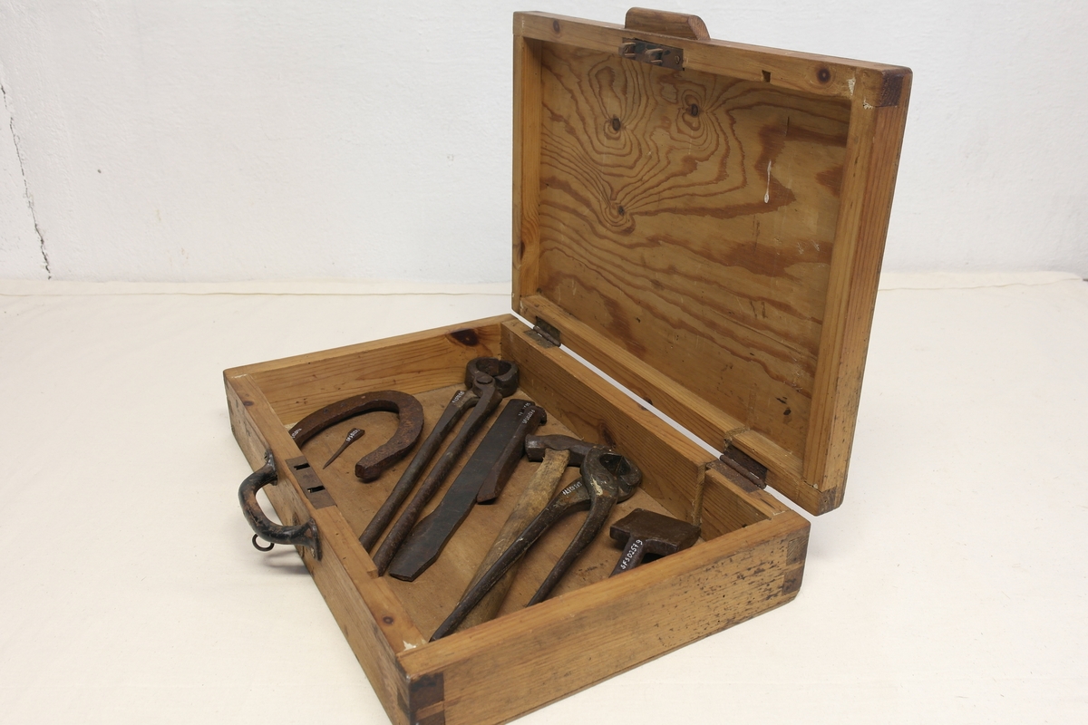 Hovslagerkasse (a) med hovslagerverktøy (b-i) i smidd jern.
A) Kasse i eik (?) med håndtak, hengsler og nøkkel. Nøkkelbeslag skiftet ut etter produksjon.
B) Tang/Brekktang. Innpreging. Til å ta av gamle sko.
C) Kniv/Hovkniv.
D) Dor/Sømdor. Til å få ut gamle søm.
E) Hammer/Klinkhammer/Skohammer. Treskaft.
F) Tang/Hovtang.
G) Jern/Klinkejern.
H) Hestesko.
I) Søm.