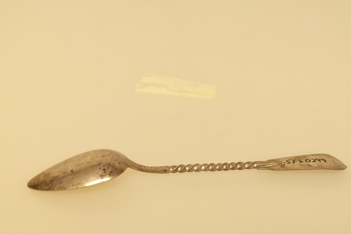 Teskje i sølv med forgylt skjeblad. Snodd skaft, nederst på skaftet har skjeen opphøyet renessansemotiv. Stemplet på baksiden av skaftet.