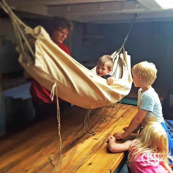 Hengekøye ombord skip, ett barn i hengekøya, to barn utenfor, én voksen bak.. Foto/Photo