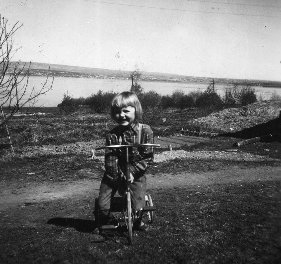 Torunn Syversen f.1952 på trehjulsykkel i Rønningen, Helgøya. Utsikt mot Mjøsa og Hamar. Kjøkkenhage.