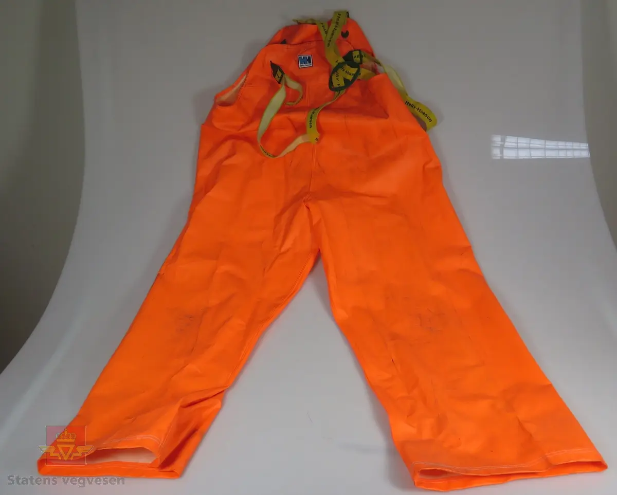 Bukse og jakke, oransje utvendig, hvite innvendig. Buksa er merket NFSM-G-00087 a, jakka er merket med b. Buksa har seler.
Størrelse, bukse 52, jakke 46/48.