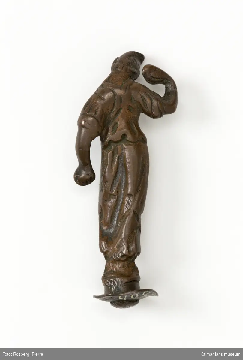 KLM 4024. Statyett, av brons. Dansande flicka i fryzisk mössa. Högra handen upplyftad. Kan eventuellt vara ett reflexornament på ljuskrona. Datering, 1600-tal.