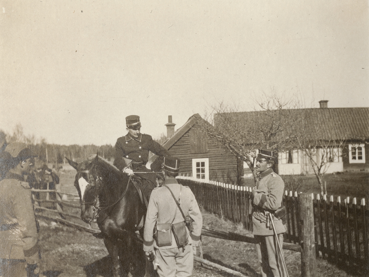 En officer på häst med tre soldater stående i givakt omkring sig.