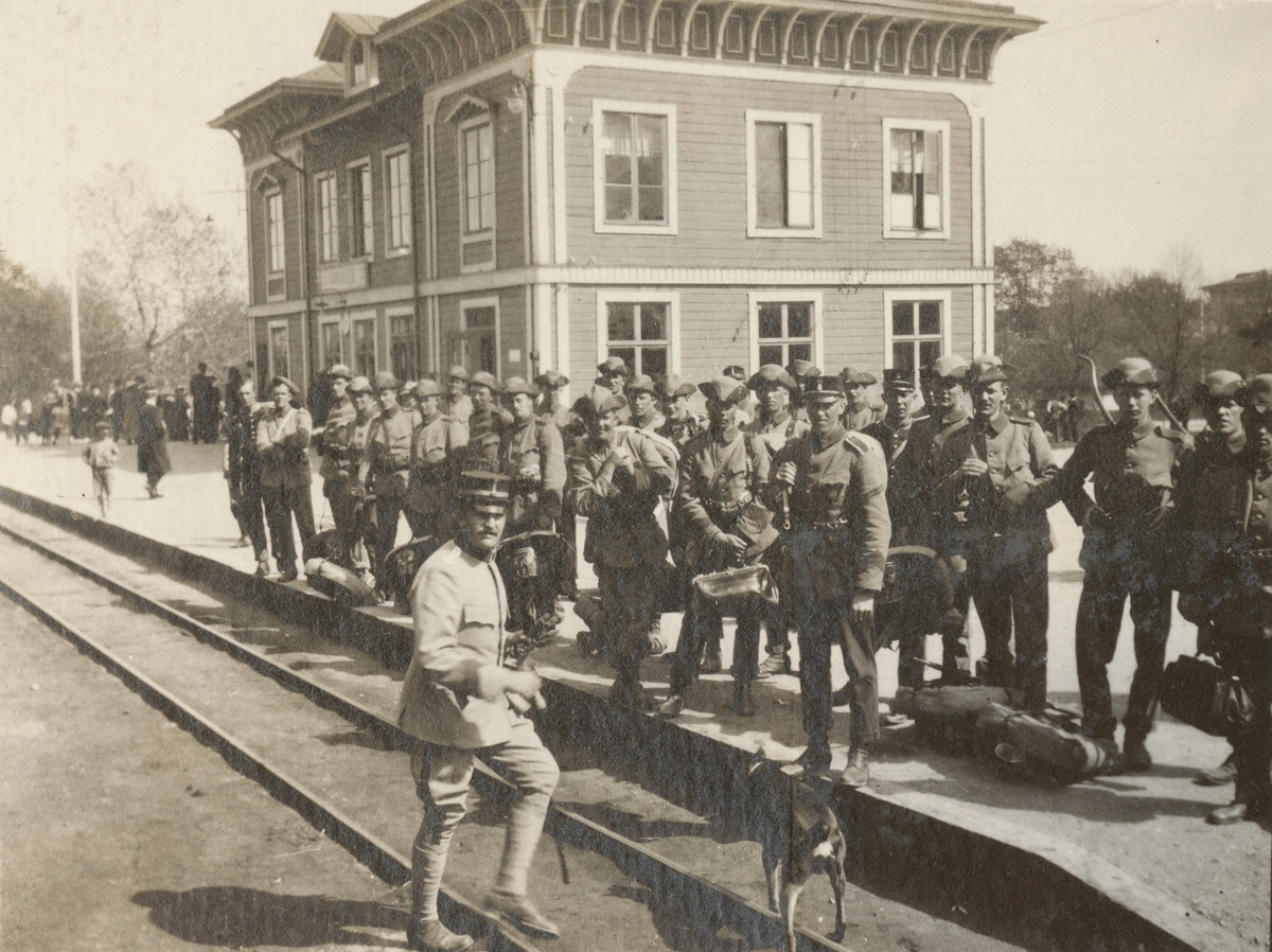 En grupp soldater samlade på tågstation inför truppförflyttning.