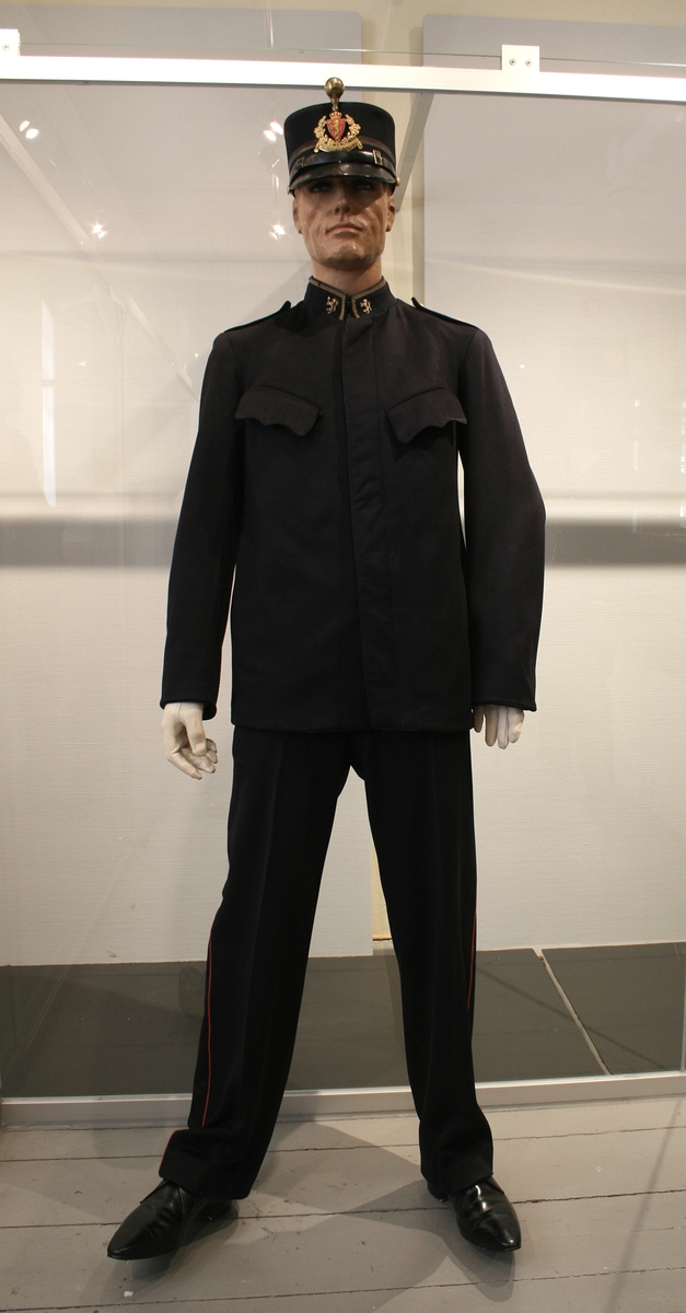 Politiuniform, jakke og bukse. Modell 1907.
Strinda politi, uniformen er i henhold til uniformsmalen av 1914. Stasjonsbetjent.
Buksa har rød passepoil.