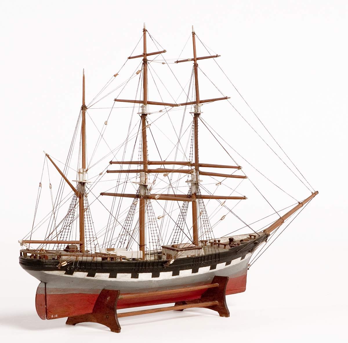 Modell av tremastad bark, handelsfartyg.
Skrå av teak.