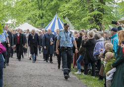 Politi går foran Kongeparet gjennom folkemengden som har møtt opp for å hylle dem under deres besøk på Hamar Middelalderfestival.