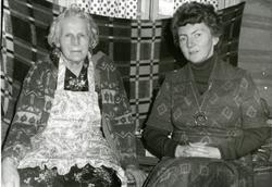 To kvinner sitter foran et et pledd som er oppspent foran et