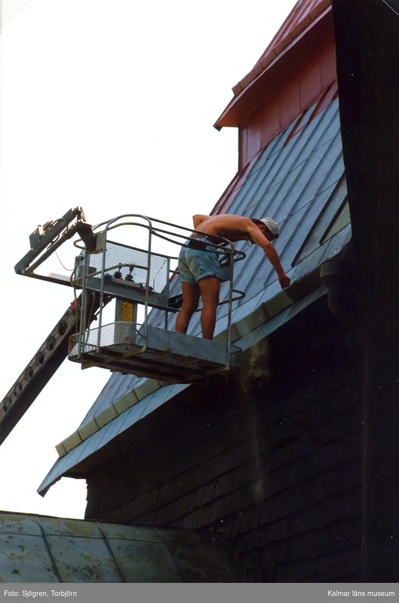 En man på en lyftkran vid taket till Frödinge kyrka.