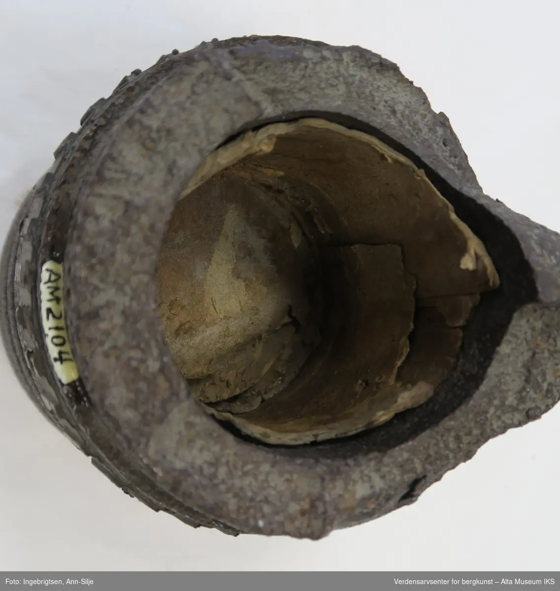 Bunnfragment av sprengt granat med rester etter styreband. Inn i fragmentet er det rester etter papp.