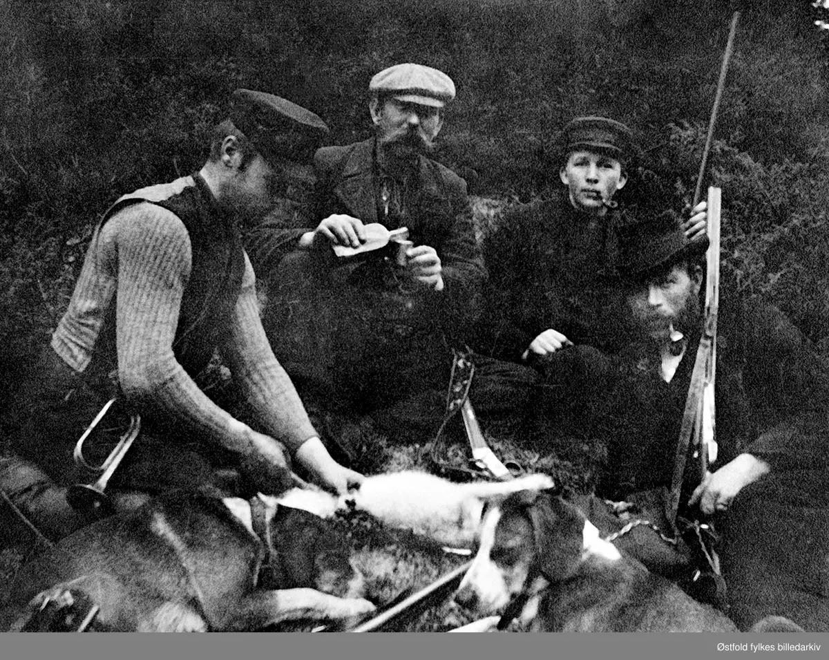 Harejakt i Lundebyskogen ca. 1902-03.
Fra venstre: Willas Lundeby (F.1879), Hans Engebrethsen(F.1856) Georg Lundeby (F.1882), Fredrik Friis Giebelhausen, fotograf Fredrikstad. De to førstnevnte var gårdbrukere. naboer på jakt, ant i Lundebyskogen. Se også ØFB.1989-00116.