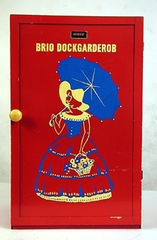 Dockgarderob av trä och masonit. Rödmålad med bild av dam med parasoll  på framsidan.
Inredd med klädstång och låda.