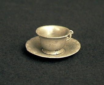Kopp med tillhörande fat (74596:2) av tenn, tillhör kaffeservis (74593-74598). Leksak.