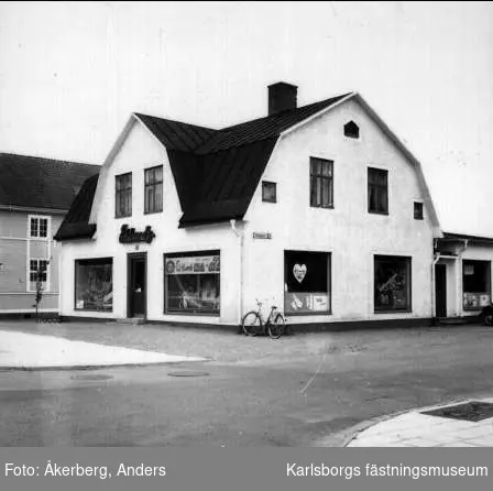 Karlsborg, Kungsgatan 10, kvarteret Boken. Eklunds Manufakturaffär. Foto: Anders Åkerberg, juli 1973. Förstoring 30 x 39 cm.