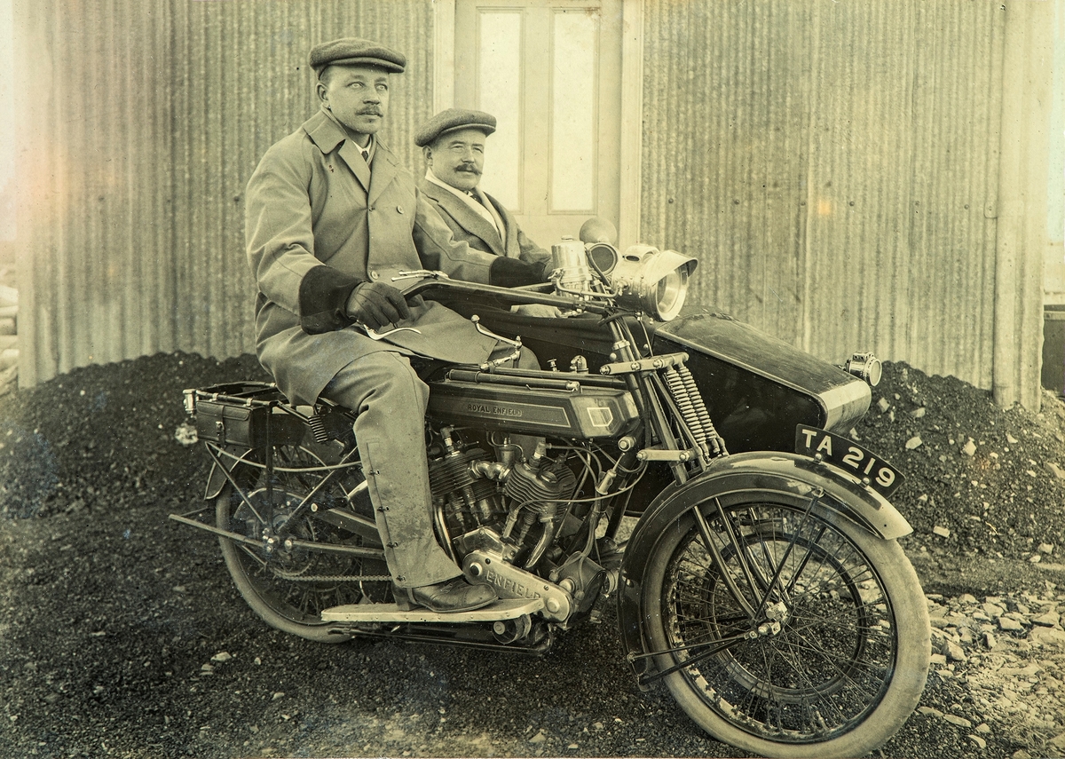 Bernhardt og Nils Skinderviken sittende på en Royal Enfield motorsykkel med sidevogn. Registrerings nummer TA 219.
Bernhard utvandret til USA, og livnærte seg der som kjendisfotograf. Bernhardt er født 27/2-1880 på gården Skinderviken på Eina, død i 1966.