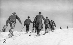 Menn, uniform, ski og skistaver, naturforhold. 
Skimarsj i 
