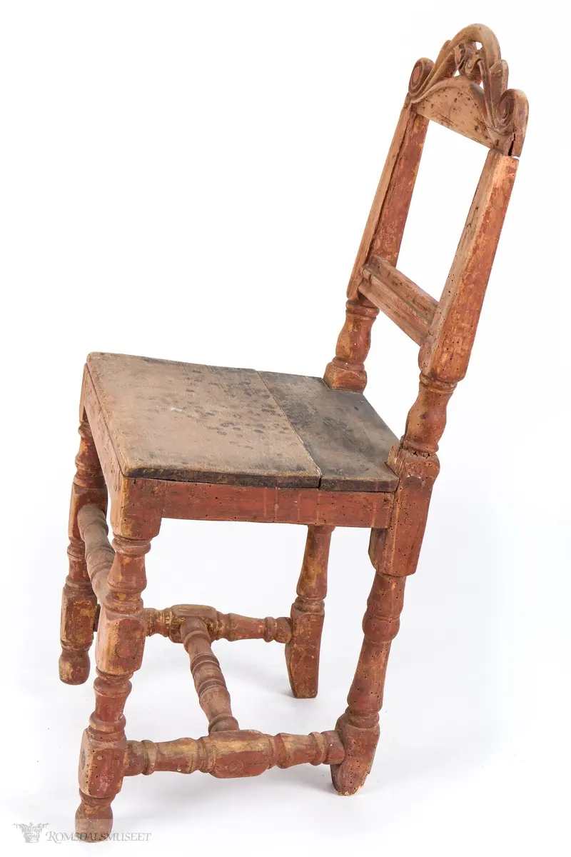 Krone med symmetrisk utskåret motiv. Volutter på sidene og et organisk motiv i midten.