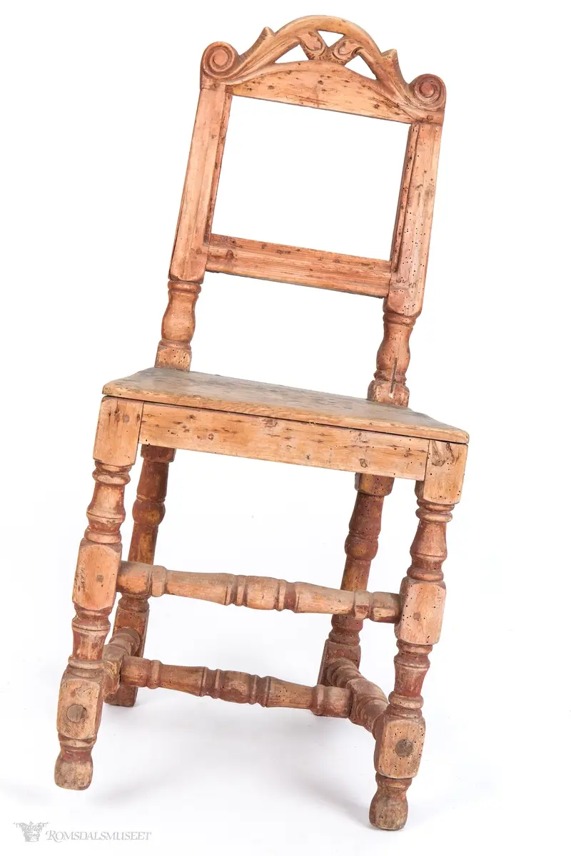 Krone med symmetrisk utskåret motiv. Volutter på sidene og et organisk motiv i midten.