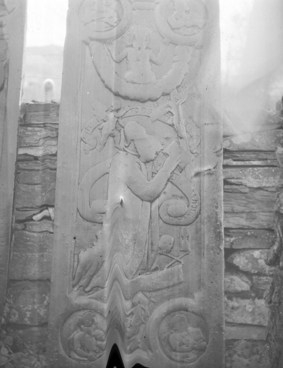 Steinplate med relieffer oppreist ved steinmur antagelig på kirkegård, religiøst motiv