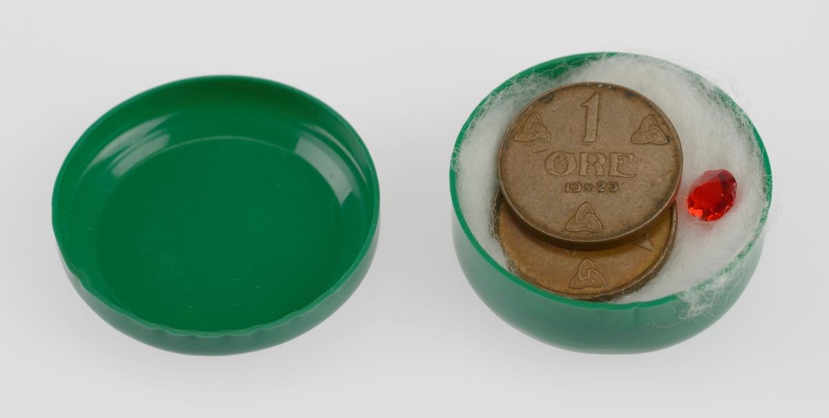 En rund liten eske laget av grønn plast. I boksen ligger det bomull og to ettøringer fra henholdsvis 1929 og 1937. Det er også en liten rød "edelstein" laget av plast i boksen. Ettøringene og "edelsteinen" er ikke merket med FTT-nummer.