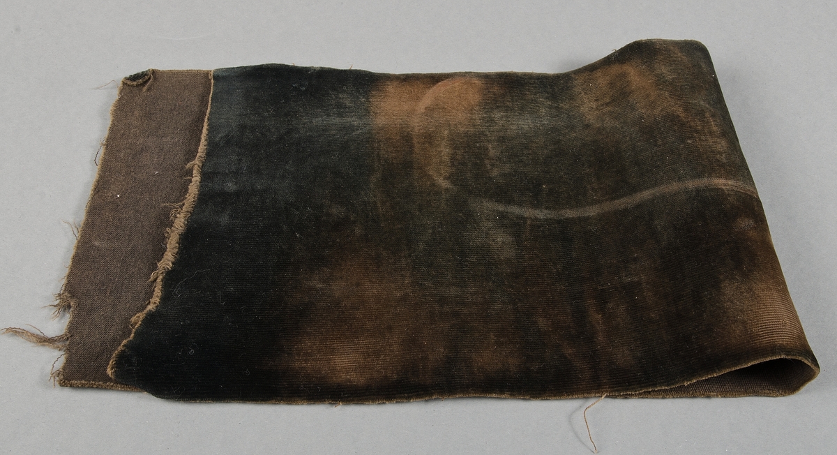 Byschong av svartbrun schagg, ofållade kanter. 