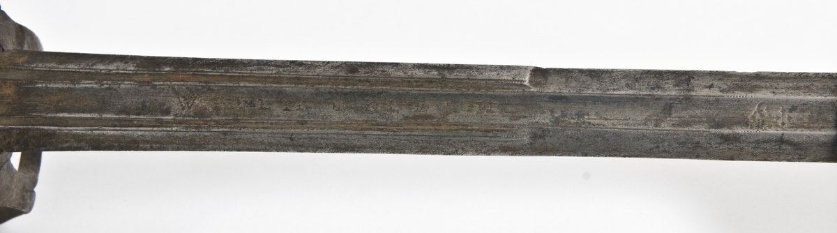 Plommeformet knapp. Tregrep  med lær bevokling.. Asymmetrisk feste med flate parerbøyler.  S formede parerstenger med utsmidde avslutninger..
Tveegget, rett klinge med rombeformet tverrsnitt og bred blodrand på begge siser 2 smale blodrender mot klingebrystet. Blodranden er merket WEILM KLEIN på begge sider. Klingen eravkortet.