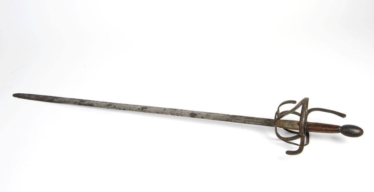 Avlang plommeformet knapp. Tregrep. Asymmetrisk feste av flate bøyler. Fremre parerstang går over i håndbøylen. Bakre parerstang nedbøyd. Sidering på utsiden med tersbøyler. Tre sidebøyler på innsiden.
Tveegget rett klinge med 6-kantett tverrsnitt og 2 korte blodrender merket MEVES / PERNS på begge sider. Klingen har 2 smedstempler på fortens fremside. Klingen er noe avkortet.