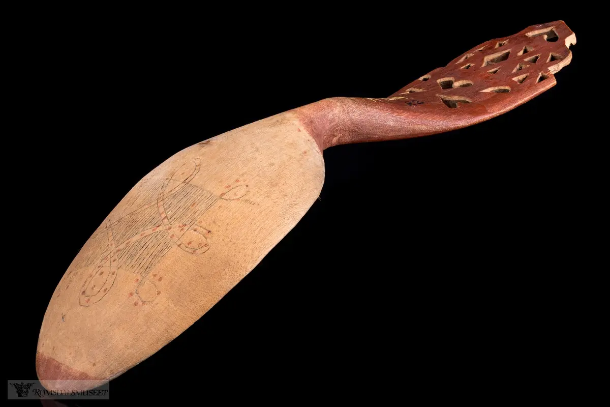 Skaftet perforert,-hjertering, selve skjeen abstrakt flate- og liljemønster med røde prikker.