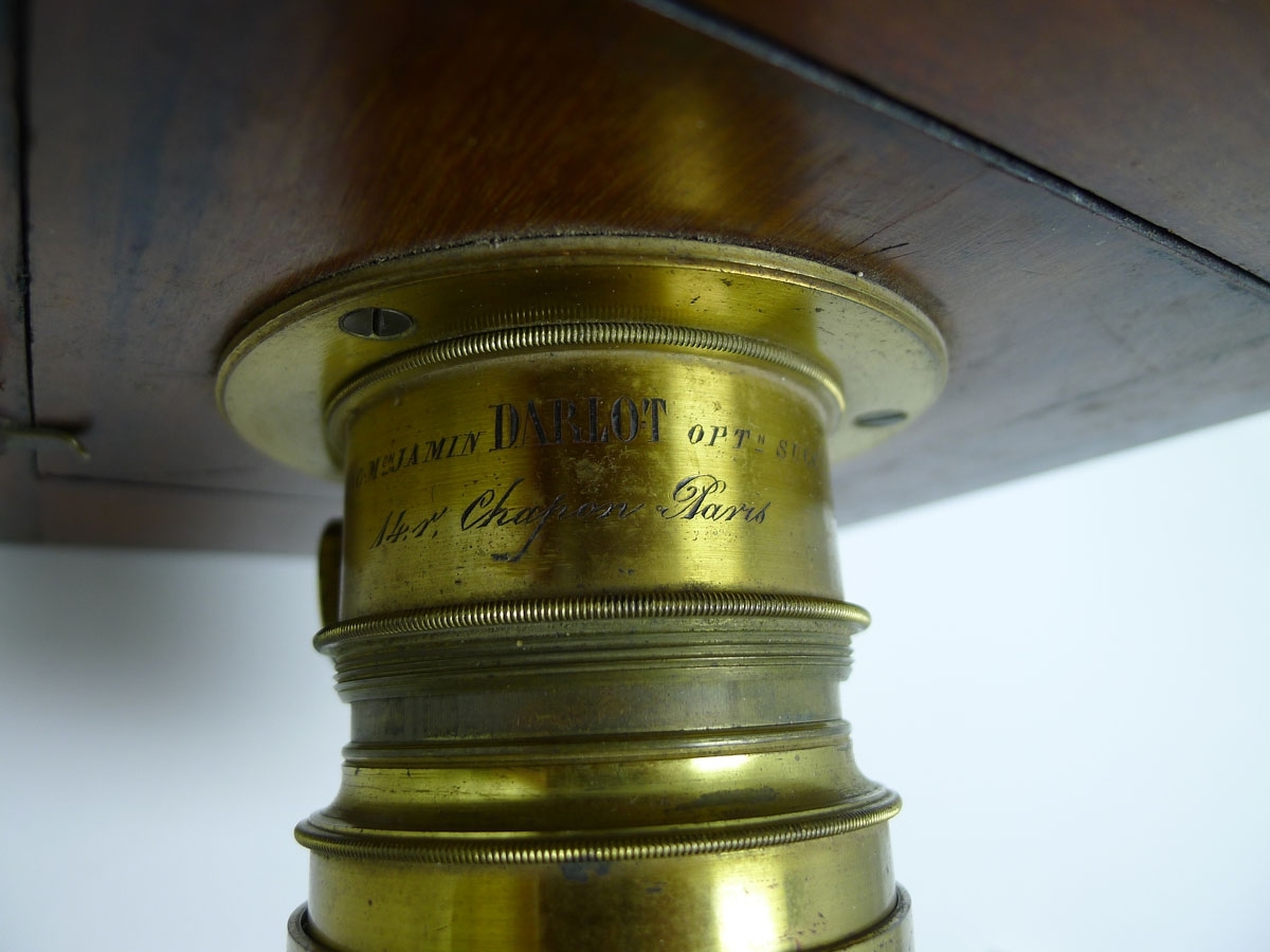 Bälgkamera från 1860-talet. Trälådan är i mahogny och linsen i mässing. På linsen står: "Anc. M.Jamin DARLOT Opt.n Succ.r. 14. r. Chapon Paris.