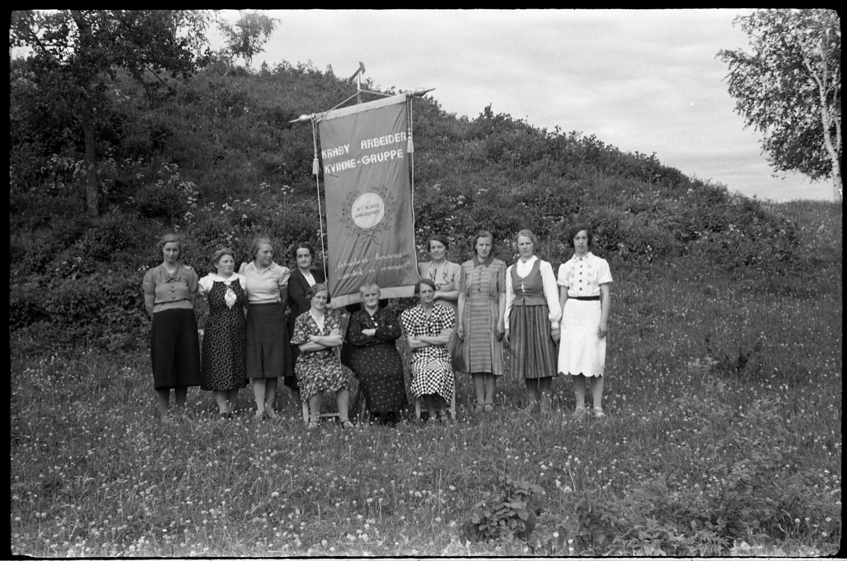 Kraby Arbeiderkvinnegruppe juni 1939. Bildene kan være tatt i forbindelse med at gruppa hadde sin nye fane klar. Serie på 6 bilder. Personene (bilde nr. 1):
Sittende foran fra venstre: Mally Tallerud, Ågot Lier, Nelly Moen. 
Bak fra venstre: Telma Moen, Ellen Lieshagen, Palma Gihleengen, Asta Hansen, Jeanette Tallerud, Mally Solberg, Marie Johansen, Anna Lieshagen.