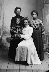 Gruppefoto av tre kvinner og en ung jente. Kvinna i den kvit