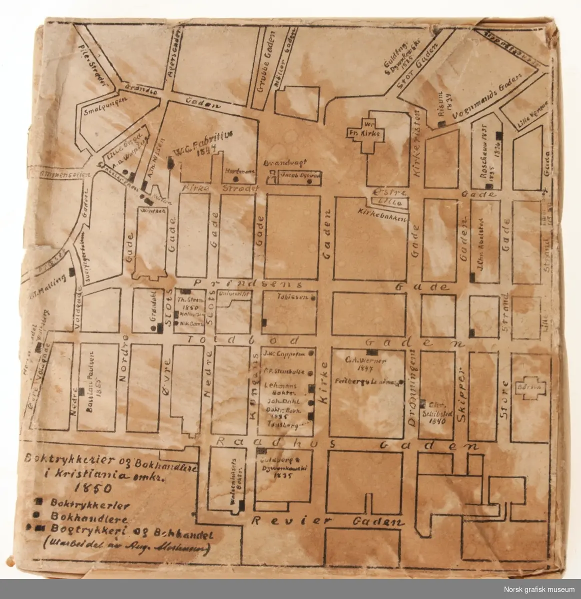 En innpakket klisje med motivet trykt på utsiden. Motivet viser et kart over boktrykkerier og bokhandlere i Kristiania omkring 1850.