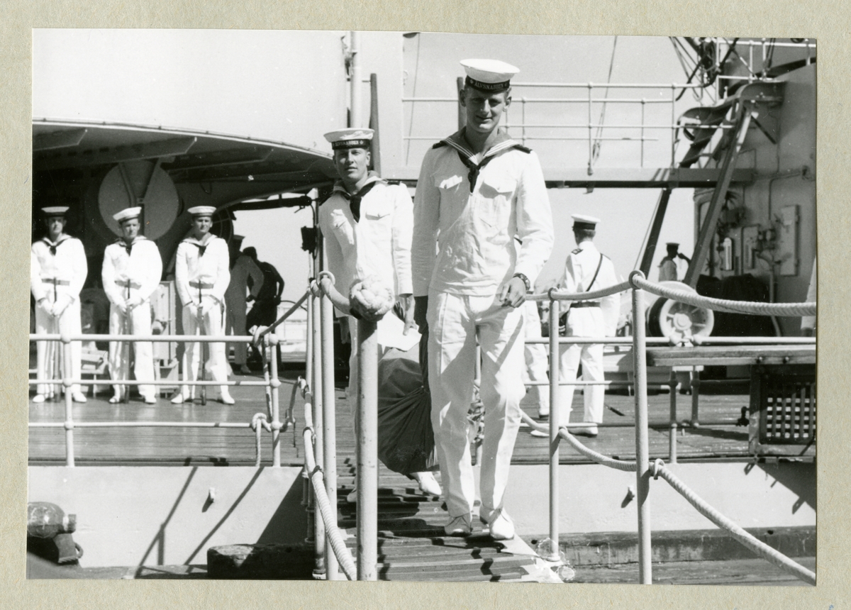 Bilden föreställer delar av den uniformsbeklädda besättningen ombord på minfartyget Älvsnabben, varav två är påväg över landgången. Bilden är tagen under fartygets långresa 1966-1967.
