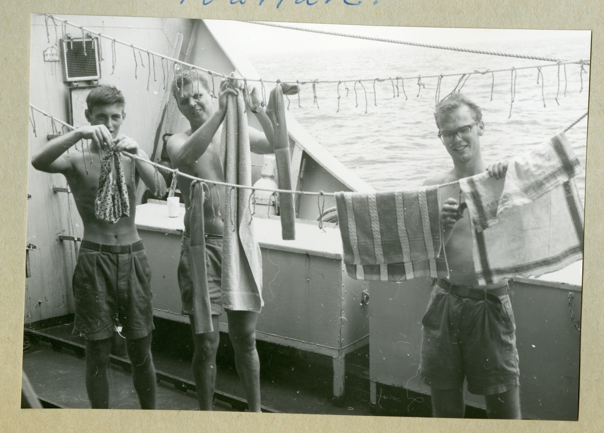Bilden föreställer tre män som hänger tvätt över tvättlinor ombord på minfartyget Älvsnabben under långresan 1966-1967.