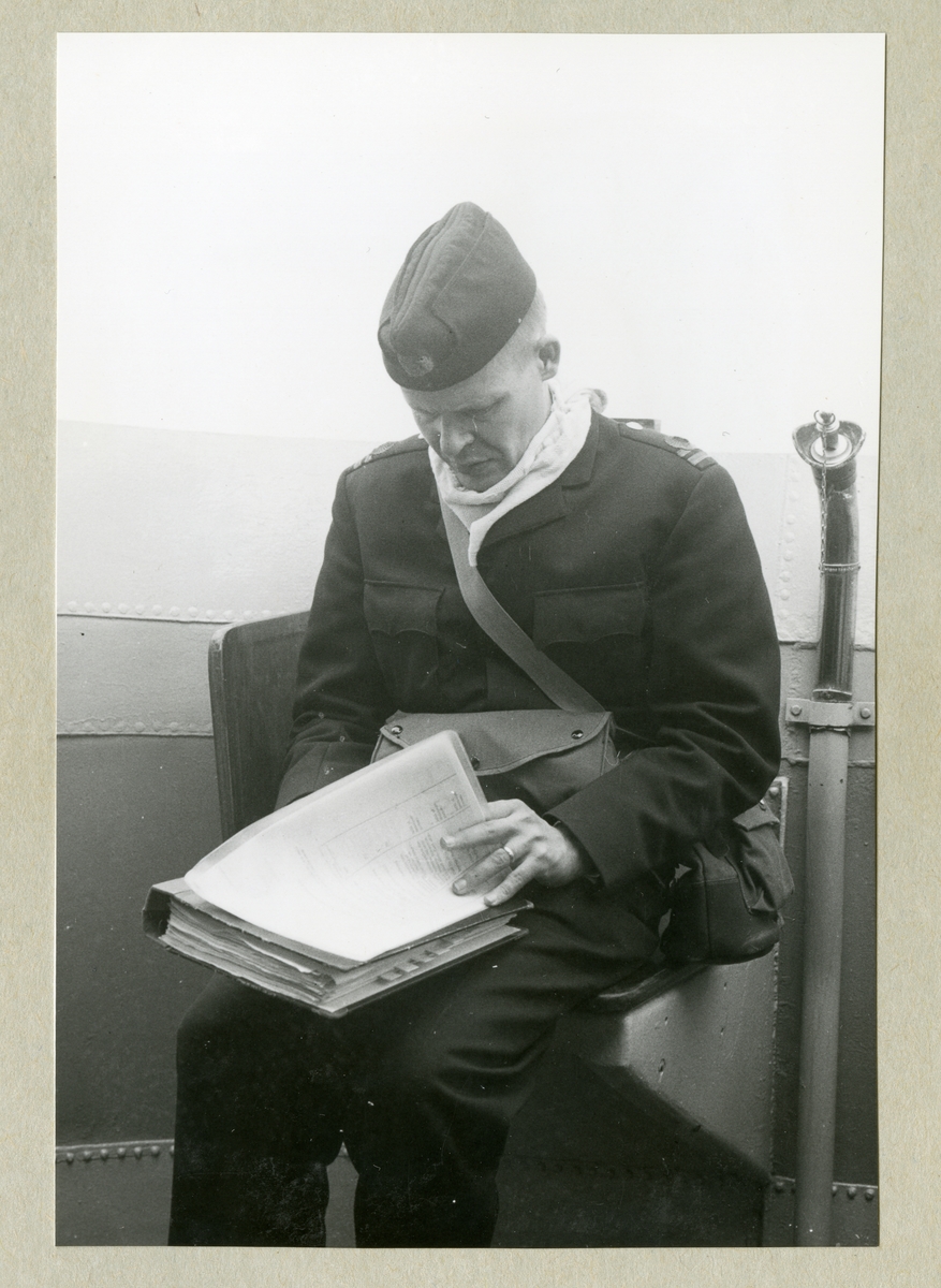 Bilden föreställer Älvsnabbens SigO (signaltjänstofficer), löjtnant Sten Swedlund, som sitter med en pärm med papper i knät ombord på minfartyget Älvsnabben under långresan 1966-1967.