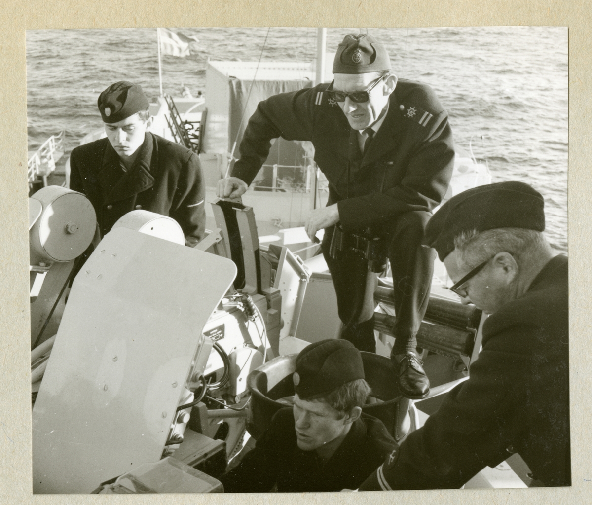 Bilden föreställer fyra uniformsklädda besättningmän vid en artilleripjäs ombord på minfartyget Älvsnabben under långresan 1966-1967.