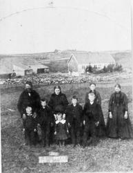 Oline og Tollak S. Bryne med 6 born på marka framfor løa og 