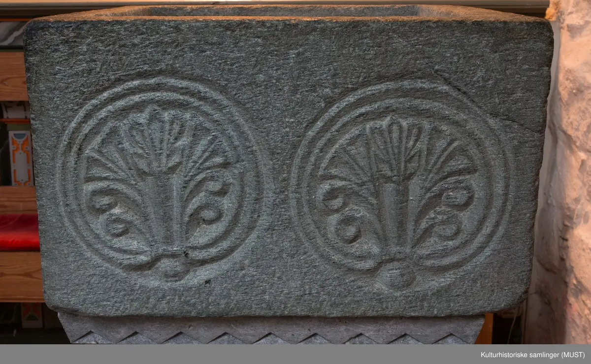 Et mønster bestående av to sidestilte palmetter inni hver sin sirkel , sees på hver side av den kvadratiske døpefontens øvre del. Enkelte steder sees også tegn på at det originalt har gått en mønster/dekorlinje langs nedre kanten.