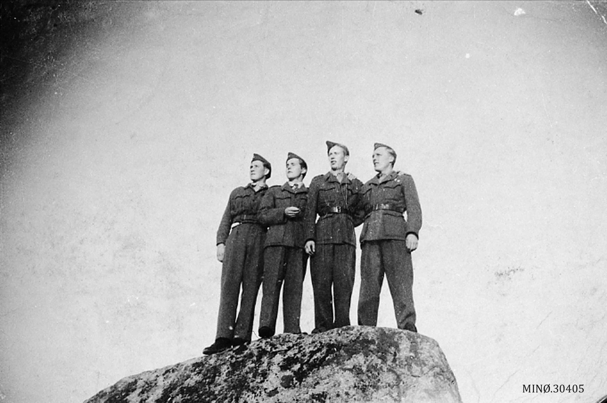 Fire uniformerte karer på toppen av en stor stein