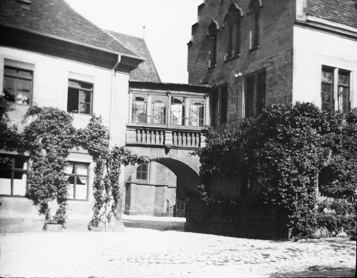 Skioptikonbild med motiv av brygga mellan två hus i Deutschhof, Heibronn.
Bilden har förvarats i kartong märkt: Resan 1908. Heilbronn 7. XXII.