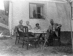 Fire personer sitter ved et bord utenfor huset til Ingvar Ha