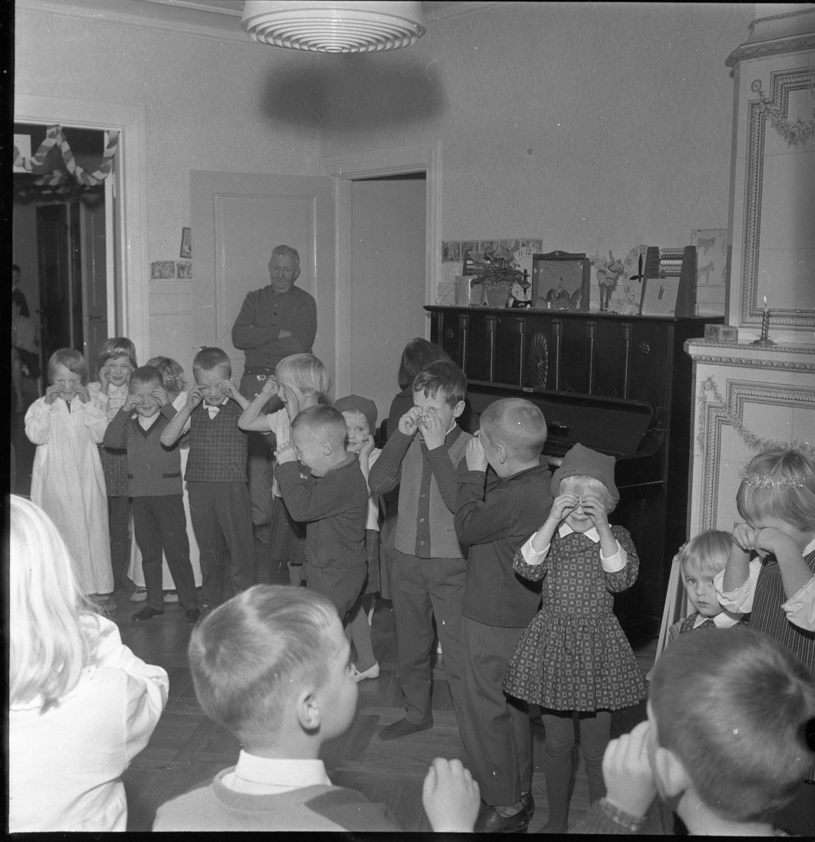 Lekskolan i Gränna, jultid 1963. Okända barn i lucialinne och tomteluva som sannolikt sjunger någon julsång.