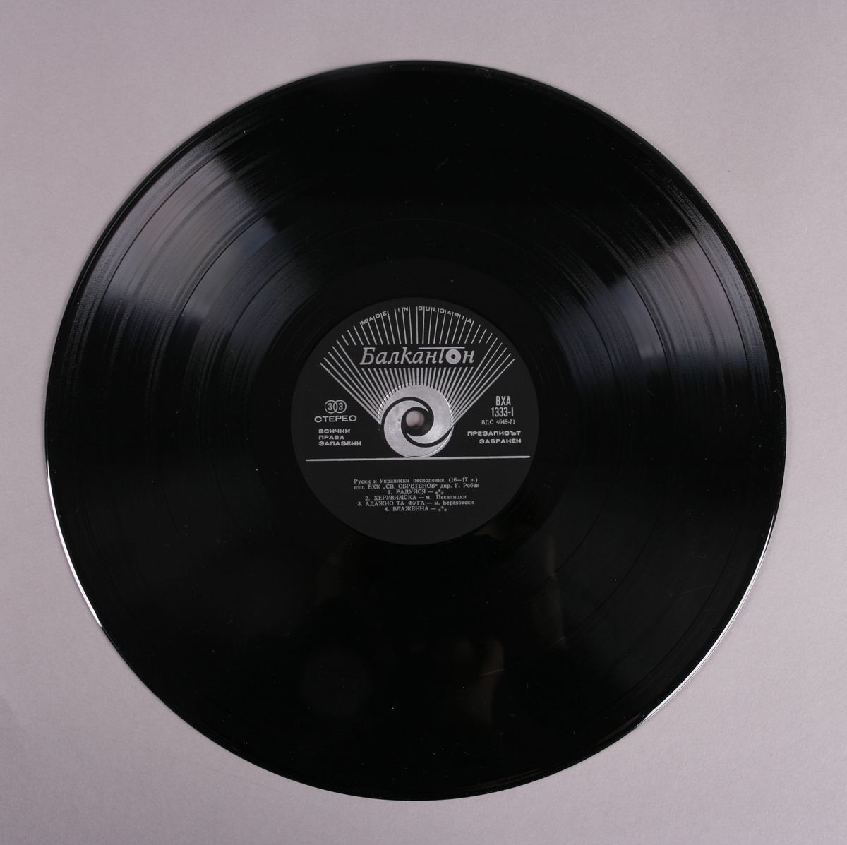 Grammofonplate i svart vinyl med plateosmalg av papir. Platen ligger i en plastlomme.