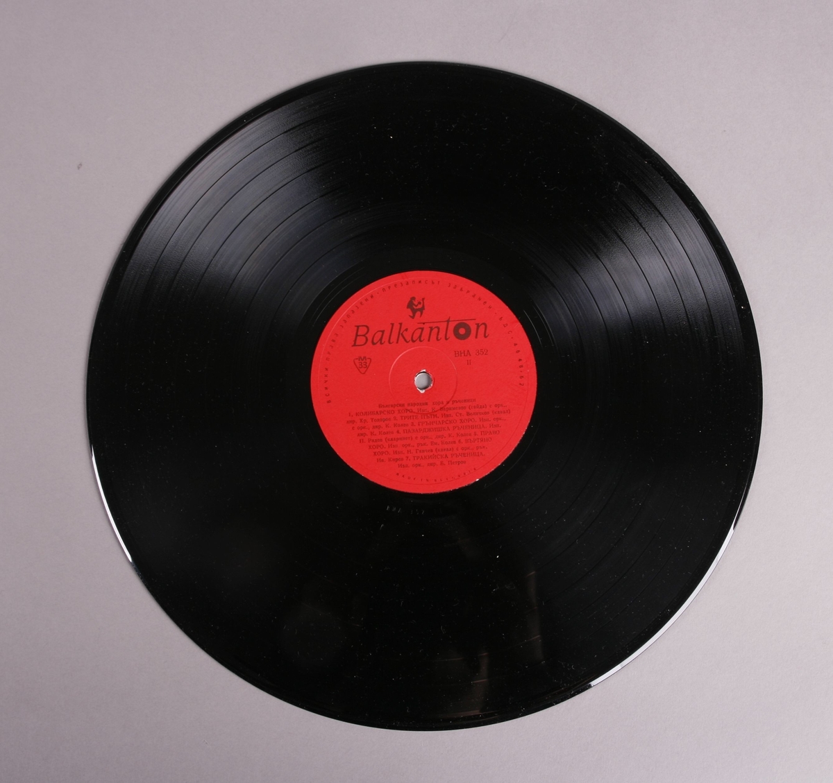 Grammofonplate i svart vinyl med plateomslag av papir. Platen ligger i en plastlomme. Det er påskrift på baksiden av plateomslaget (se bilde).