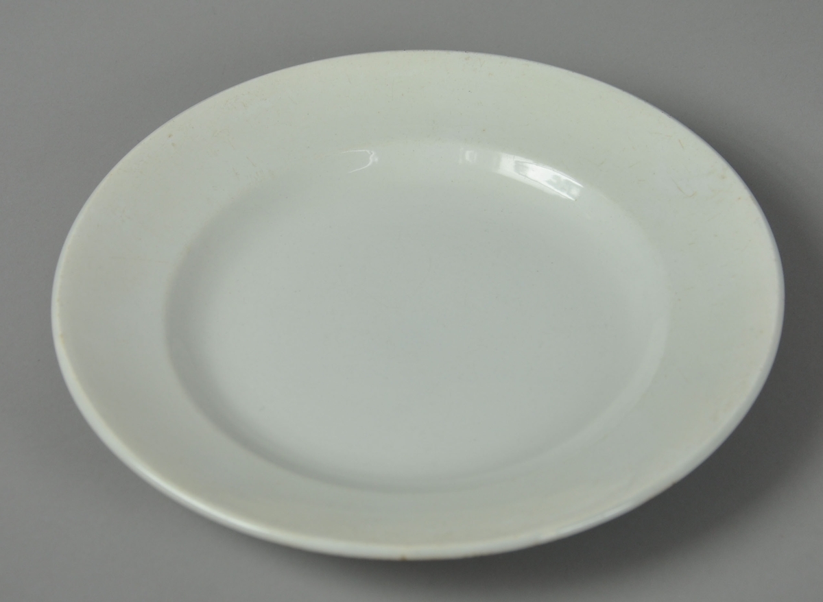 Hvit tallerken av glassert keramikk.