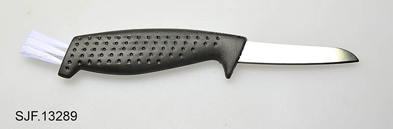 Soppkniven er kjøpt inn i forbindelse med utstillingen "TRÅKK". Den har et knivblad, et skaft av grønn plast, og en kost i enden av skaftet. Til kniven tilhører det ei slire i svart skinn. Det er et svart nylonsnøre festet i slira. 