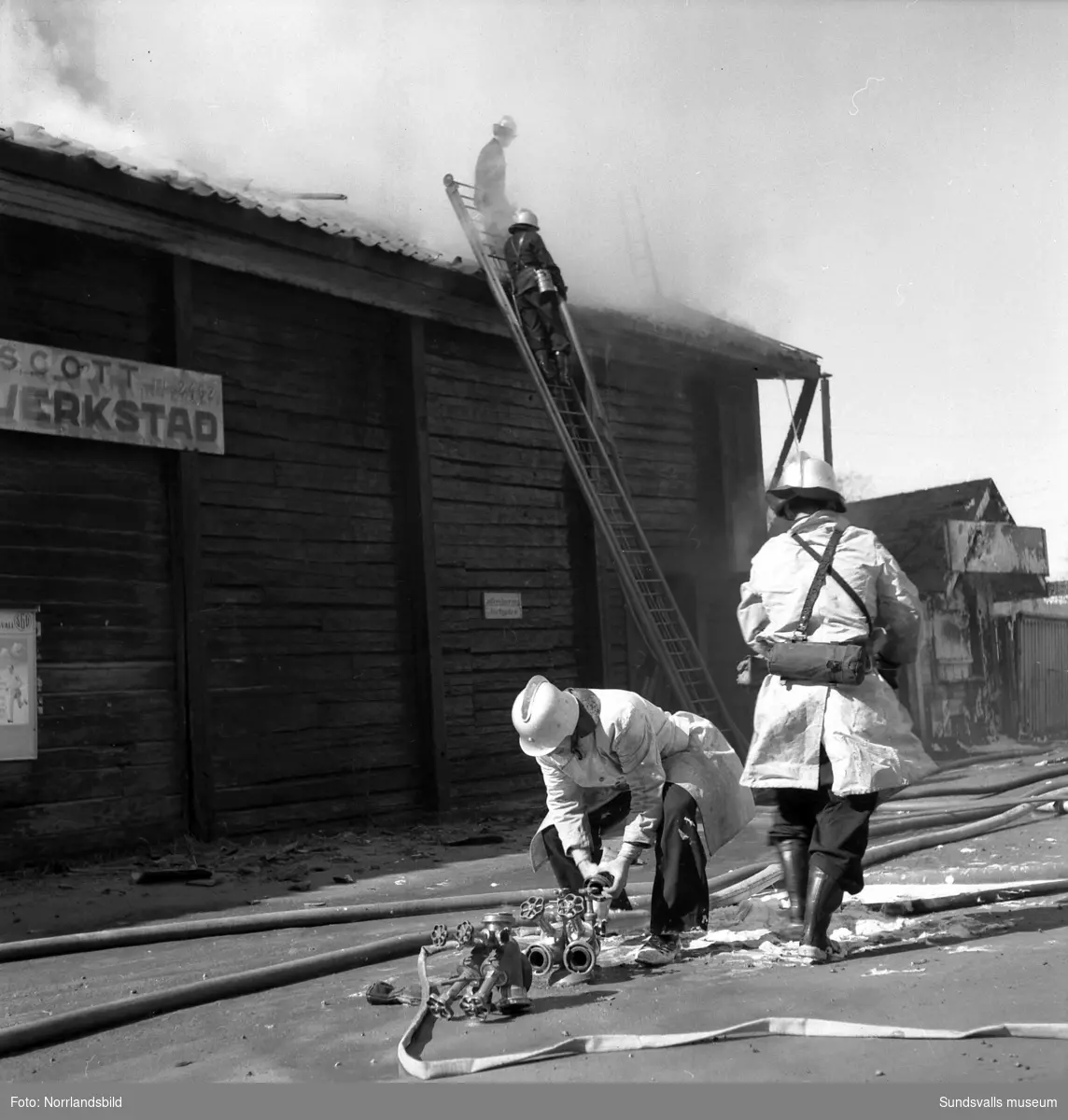 En brand i den gamla vinfabriken som då låg väster om Grönborgs bryggeri. Brandmännen jobbar med att släcka elden som uppstått i den västra delen av byggnaden och även en liten kiosk vid byggnadens västra gavel är hotad. Hela den timrade byggnaden flyttades senare till Norra berget.