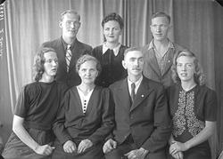 Gruppebilde. Familiegruppe på syv. Eldre kvinne, eldre mann,