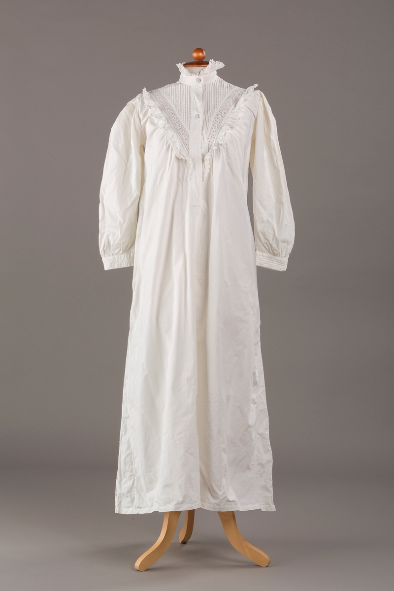 Form: Lange ermer, fotsid.

Blondekant og rysjer i halsåpning.
To knapper i metall kledd i tekstil. Mangler en knapp.